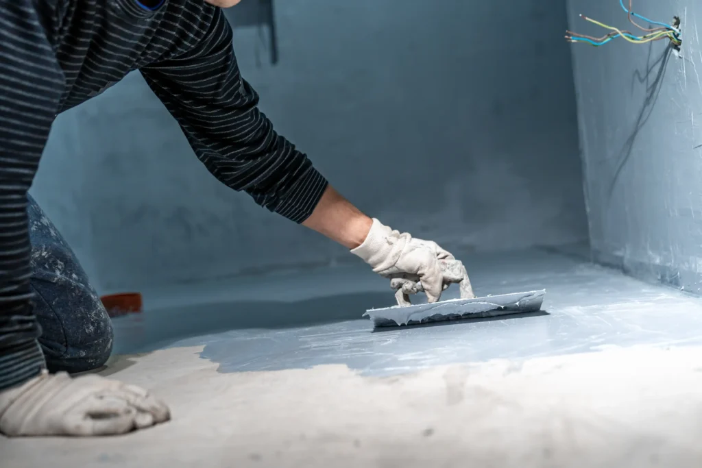 damp-and-rain-penetration Man applying waterproof damp layer to flooring and walls.